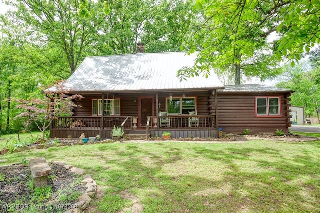 log-style house featuring covered porch, a chimney, a front yard, and log exterior