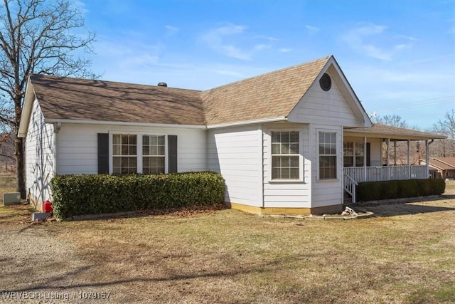 back of house with covered porch, a shingled roof, and a yard