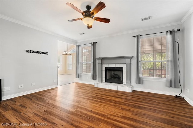 unfurnished living room featuring hardwood / wood-style floors, ceiling fan with notable chandelier, crown molding, and a tiled fireplace