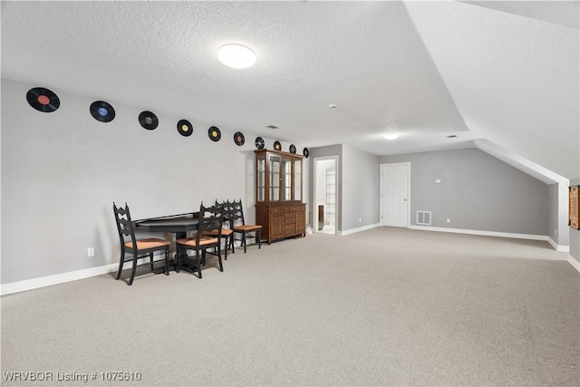 carpeted dining space featuring lofted ceiling and a textured ceiling