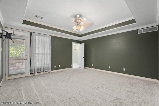 empty room with a tray ceiling, ceiling fan, light carpet, and ornamental molding