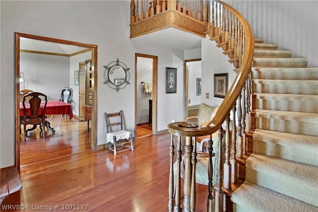 stairway featuring wood-type flooring and a high ceiling