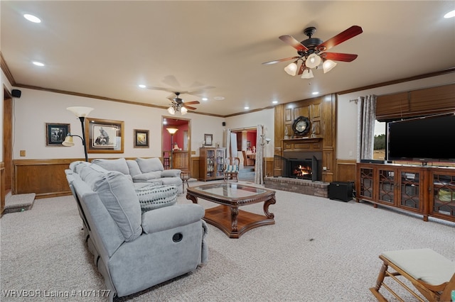 carpeted living room featuring a fireplace, ornamental molding, and ceiling fan