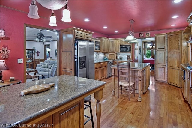 kitchen featuring a center island, hanging light fixtures, a breakfast bar, and appliances with stainless steel finishes