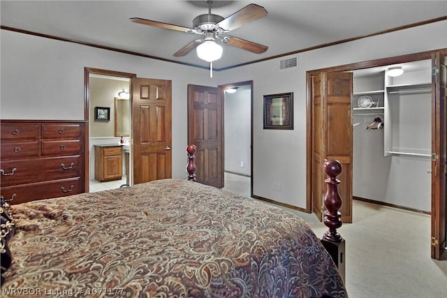 bedroom with crown molding, ceiling fan, ensuite bath, and a closet