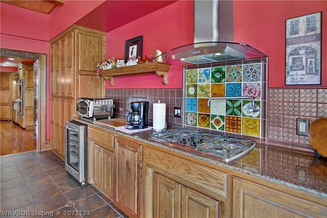 kitchen with wine cooler, island exhaust hood, stainless steel gas cooktop, and backsplash