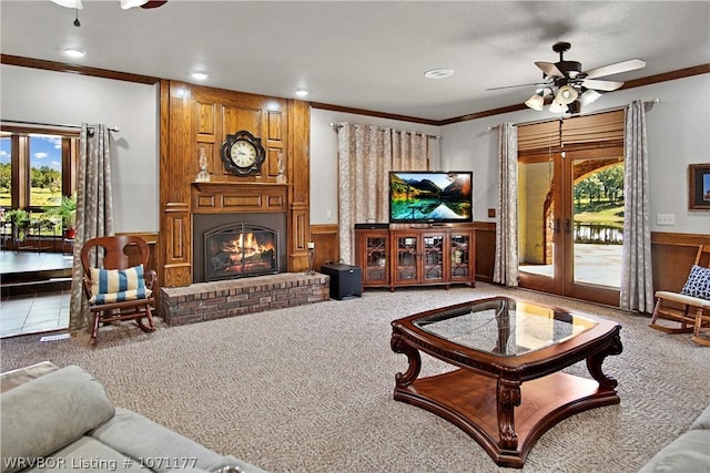 living room with carpet flooring, ceiling fan, a brick fireplace, wood walls, and ornamental molding