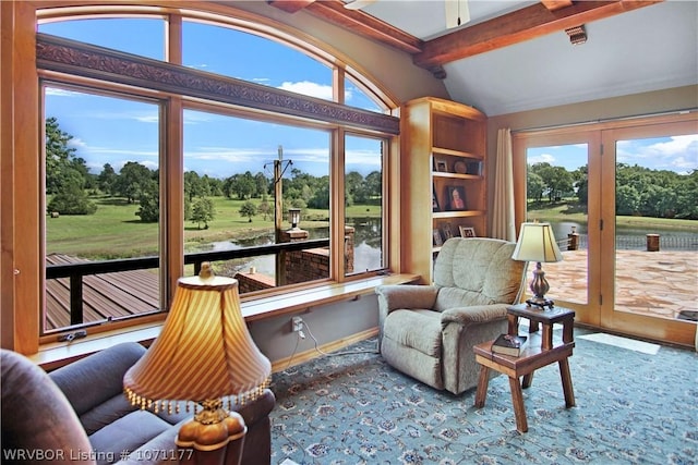 sitting room with a water view and vaulted ceiling with beams