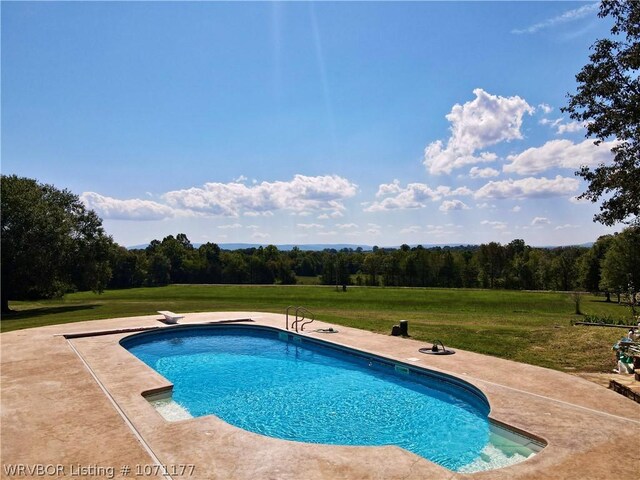 view of pool featuring a diving board, a lawn, and a patio