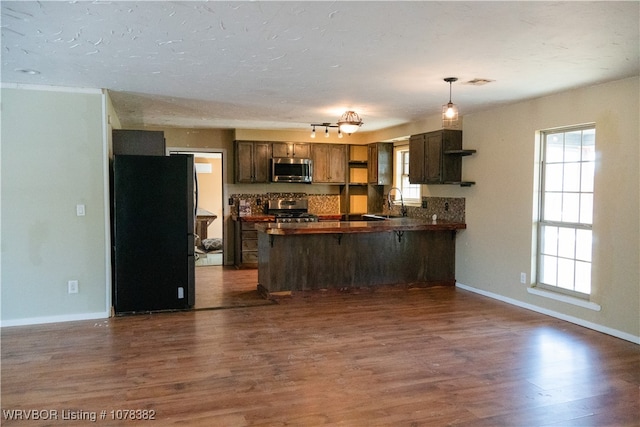 kitchen with kitchen peninsula, dark hardwood / wood-style floors, decorative light fixtures, stainless steel appliances, and sink