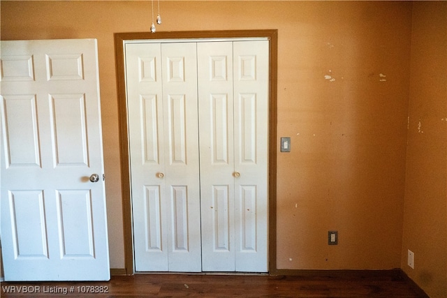 unfurnished bedroom with a closet and dark wood-type flooring