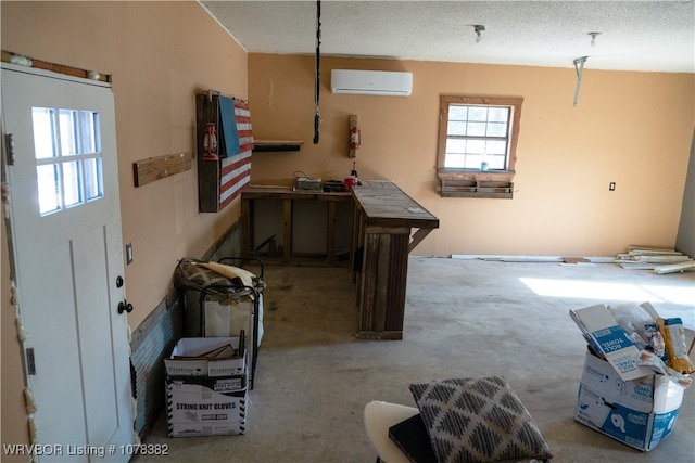 interior space featuring a workshop area, a textured ceiling, a wealth of natural light, and a wall mounted air conditioner