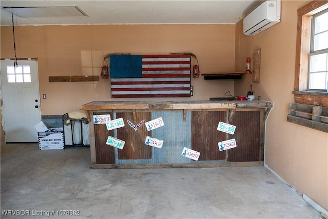 kitchen with decorative light fixtures, an AC wall unit, and concrete floors