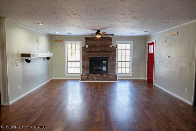 unfurnished living room featuring a brick fireplace, ornamental molding, a wealth of natural light, and dark hardwood / wood-style floors