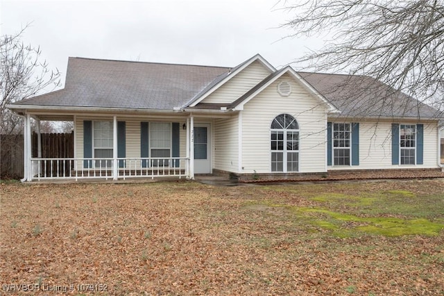 single story home featuring covered porch, a shingled roof, and a front yard