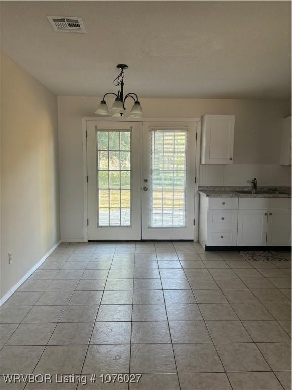 interior space with sink, light tile patterned floors, french doors, and an inviting chandelier