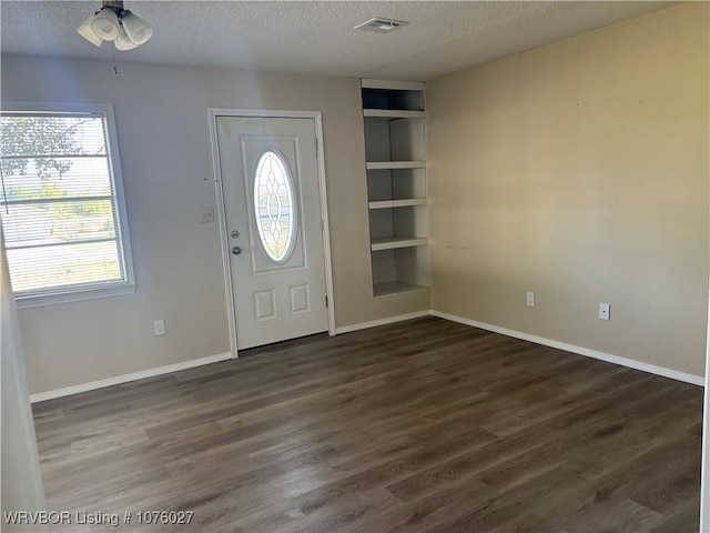 foyer with plenty of natural light, dark hardwood / wood-style floors, a textured ceiling, and ceiling fan