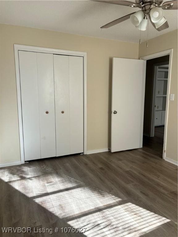 unfurnished bedroom featuring ceiling fan, a closet, and dark wood-type flooring