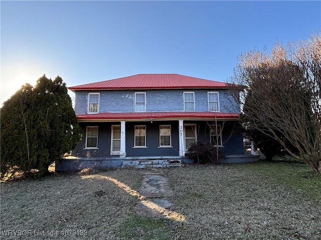 view of front of house with metal roof, a porch, and a front lawn