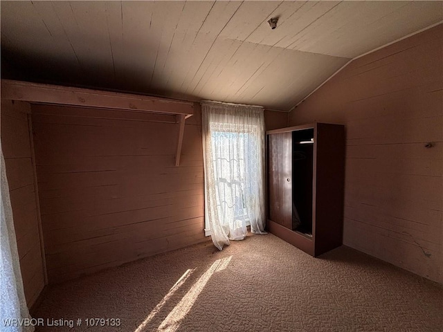 carpeted empty room with lofted ceiling, wood walls, and wooden ceiling