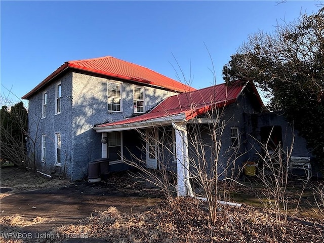 rear view of property with metal roof and stucco siding