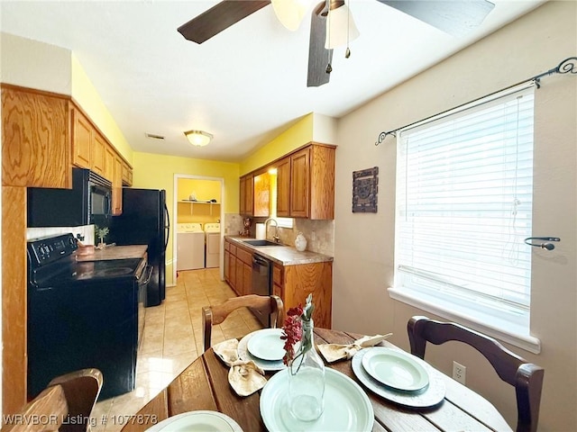 kitchen with a healthy amount of sunlight, sink, black appliances, and washing machine and clothes dryer