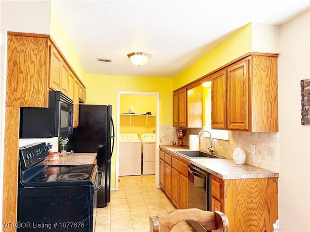 kitchen featuring backsplash, sink, washer and dryer, light tile patterned floors, and black appliances