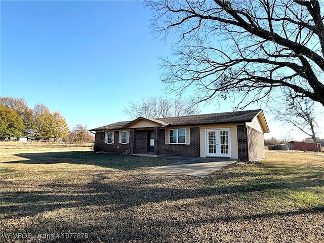 ranch-style home with a front lawn, a patio, and french doors