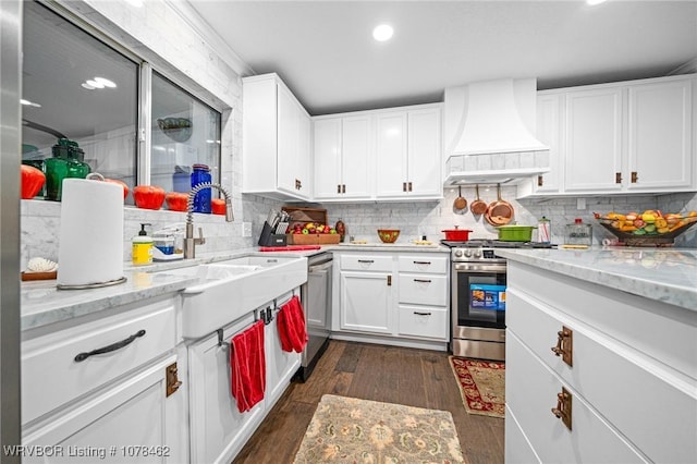 kitchen featuring custom exhaust hood, white cabinetry, dark wood-type flooring, stainless steel appliances, and light stone counters