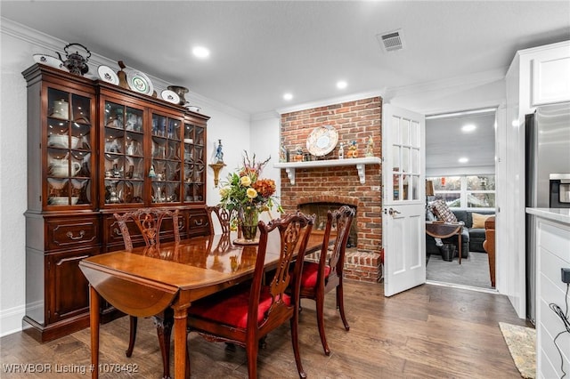 dining area with a fireplace, dark wood-type flooring, and crown molding