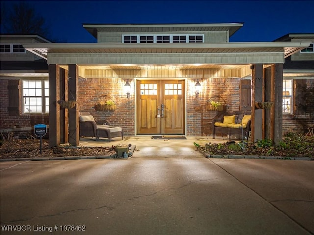 exterior entry at twilight featuring a porch and brick siding