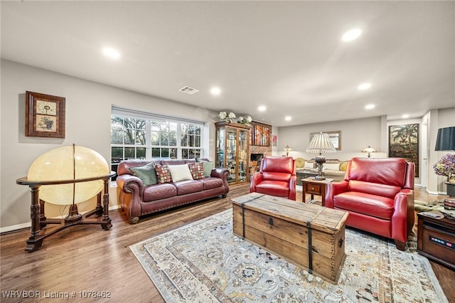 living room with a brick fireplace and light hardwood / wood-style floors