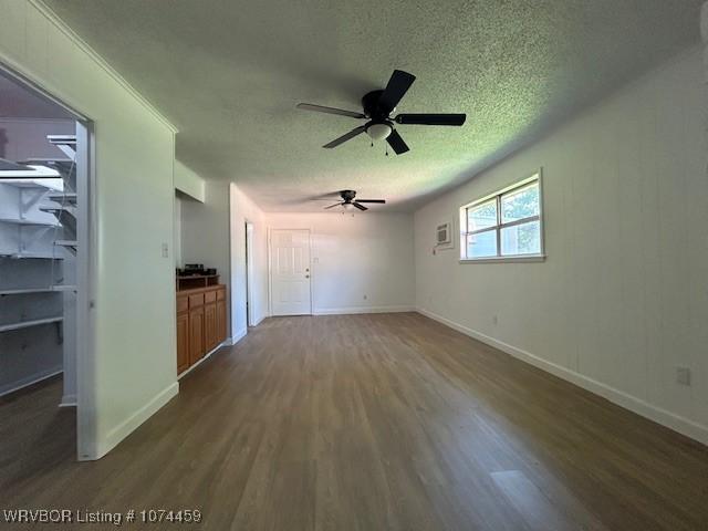 unfurnished living room featuring a textured ceiling, ceiling fan, and dark wood-type flooring