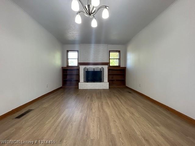 unfurnished living room with hardwood / wood-style flooring, a fireplace, and an inviting chandelier