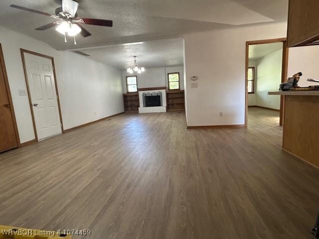 unfurnished living room with hardwood / wood-style floors, ceiling fan with notable chandelier, and a textured ceiling