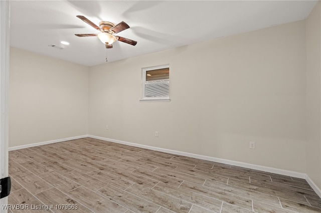 spare room featuring visible vents, baseboards, wood finished floors, and a ceiling fan