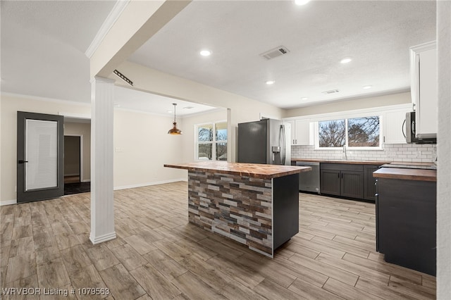 kitchen featuring visible vents, wood finish floors, stainless steel appliances, tasteful backsplash, and butcher block counters