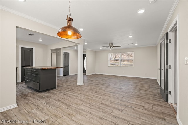 interior space featuring visible vents, light wood finished floors, a kitchen island, ornamental molding, and butcher block counters