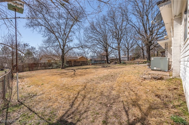 view of yard featuring a trampoline, central AC unit, and a fenced backyard