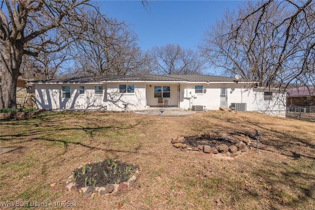 rear view of house with fence, central AC, metal roof, a yard, and a patio