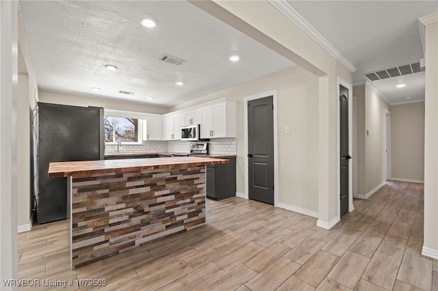 kitchen with visible vents, butcher block countertops, white cabinets, and appliances with stainless steel finishes