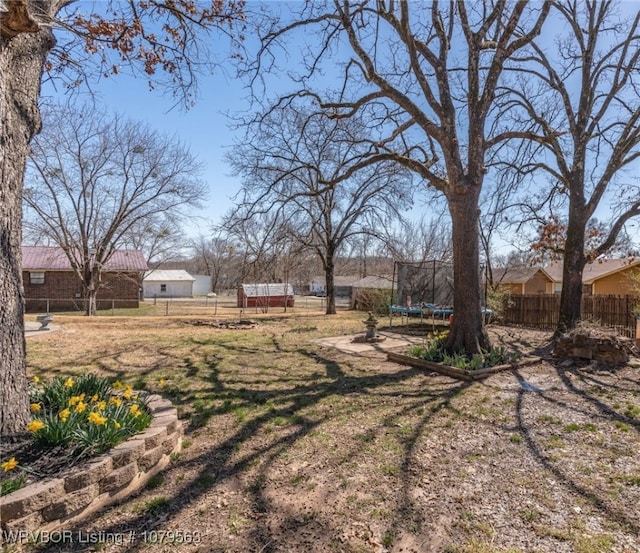 view of yard with a trampoline and fence