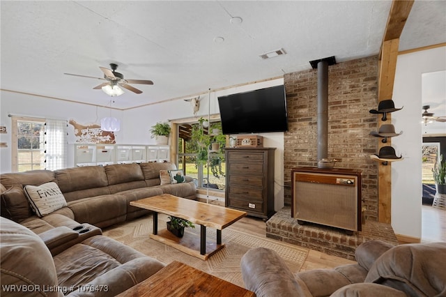 living room with a wood stove, light hardwood / wood-style flooring, and ceiling fan