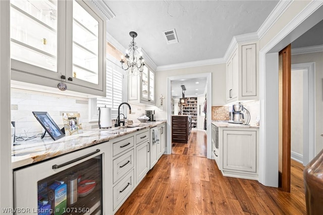 kitchen featuring sink, crown molding, dark hardwood / wood-style floors, light stone countertops, and white cabinets