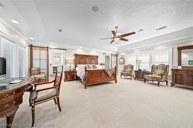 carpeted bedroom featuring a tray ceiling, ornamental molding, a barn door, and ceiling fan