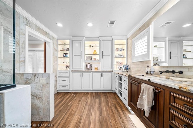 kitchen featuring ornamental molding, dark hardwood / wood-style floors, white cabinets, and light stone counters