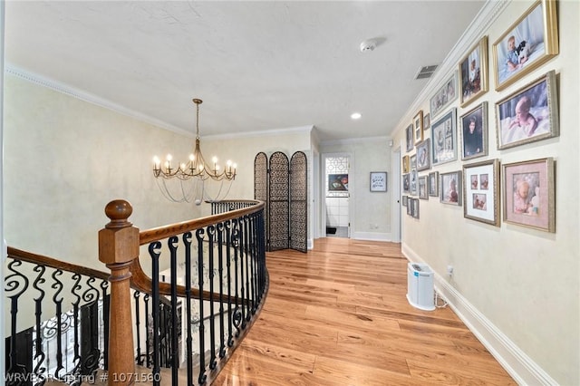 hallway featuring crown molding, hardwood / wood-style floors, and an inviting chandelier