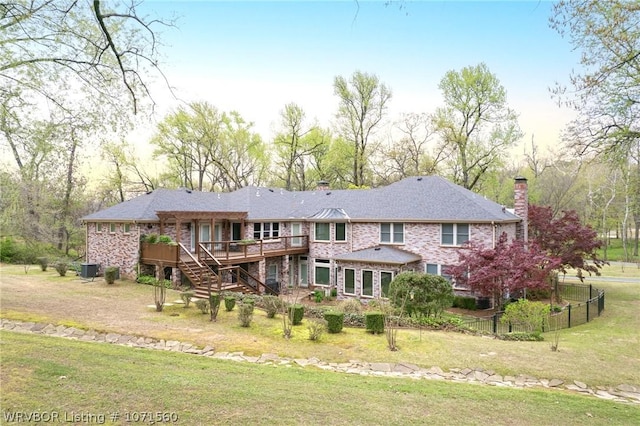 rear view of house featuring a wooden deck, a yard, and cooling unit