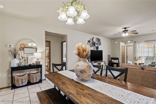 dining area with light tile patterned floors and ceiling fan with notable chandelier