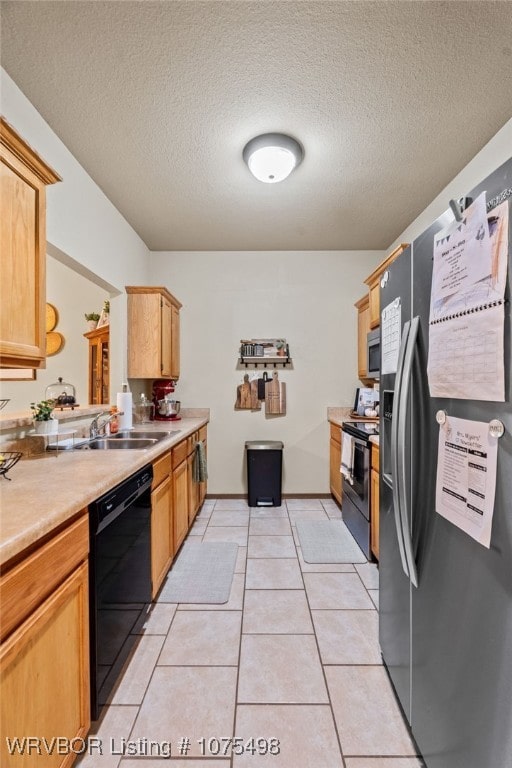 kitchen featuring light brown cabinetry, a textured ceiling, stainless steel appliances, sink, and light tile patterned floors